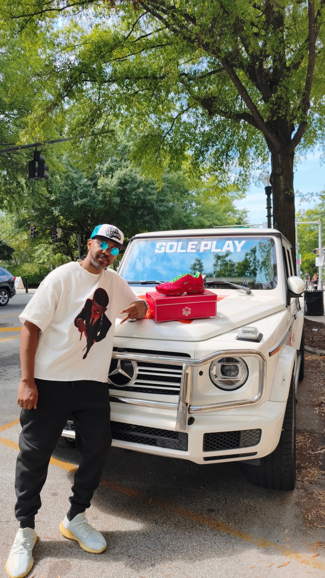 Community member wearing OctaveATL apparel beside a white Mercedes G-Class